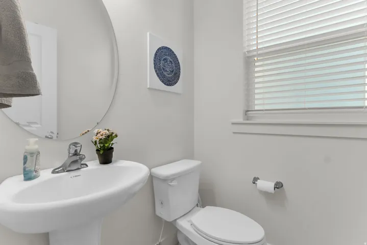 White pedestal sink with a chrome faucet and a circular wall mirror