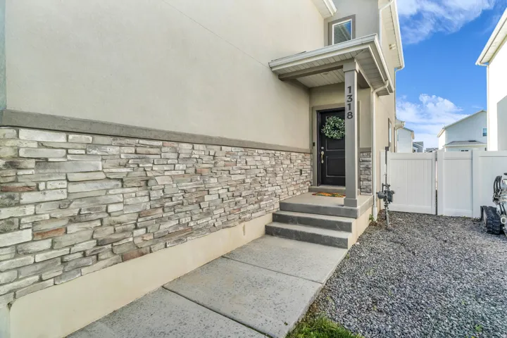Exterior featuring stacked stone veneer accents, a covered front entry, and a privacy fence