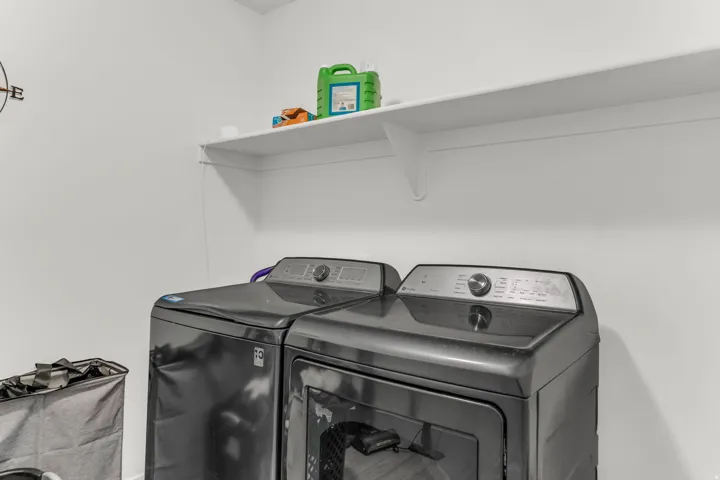 Laundry area featuring white walls and a white wall-mounted shelf