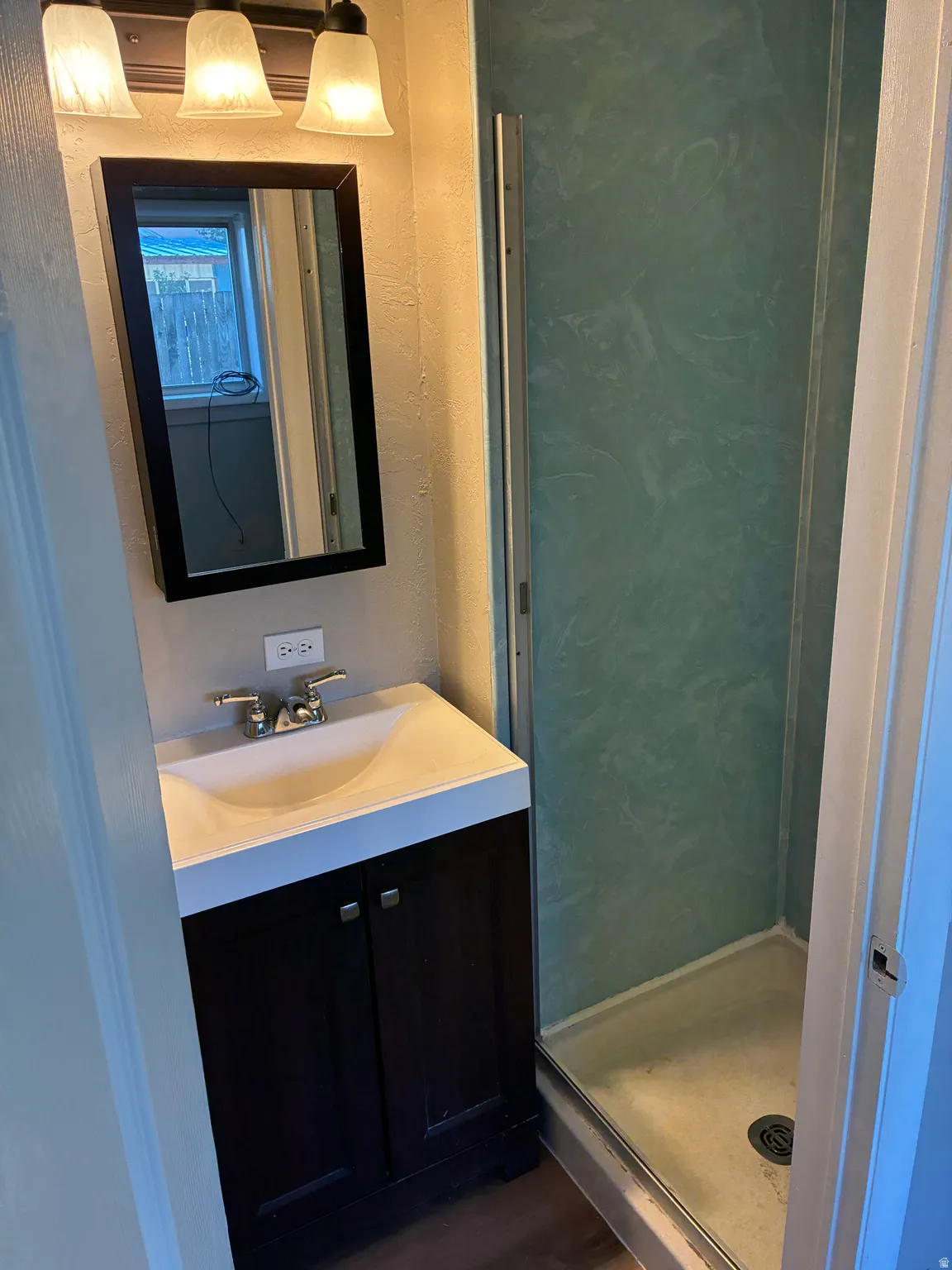 Bathroom featuring a dark wood-finish vanity, integrated sink, and a framed mirror