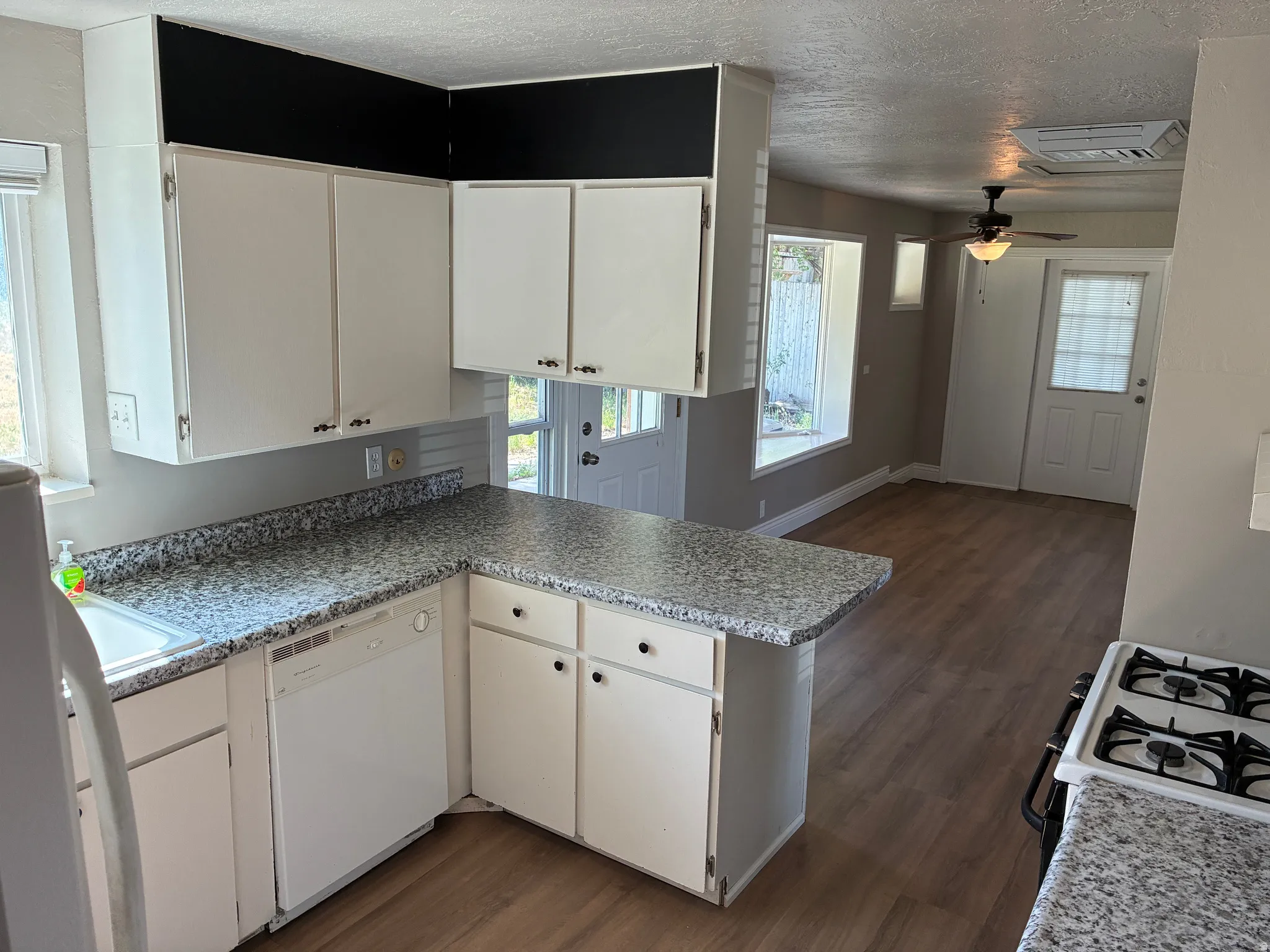 Kitchen featuring white cabinetry, speckled countertops, and a white built-in dishwasher