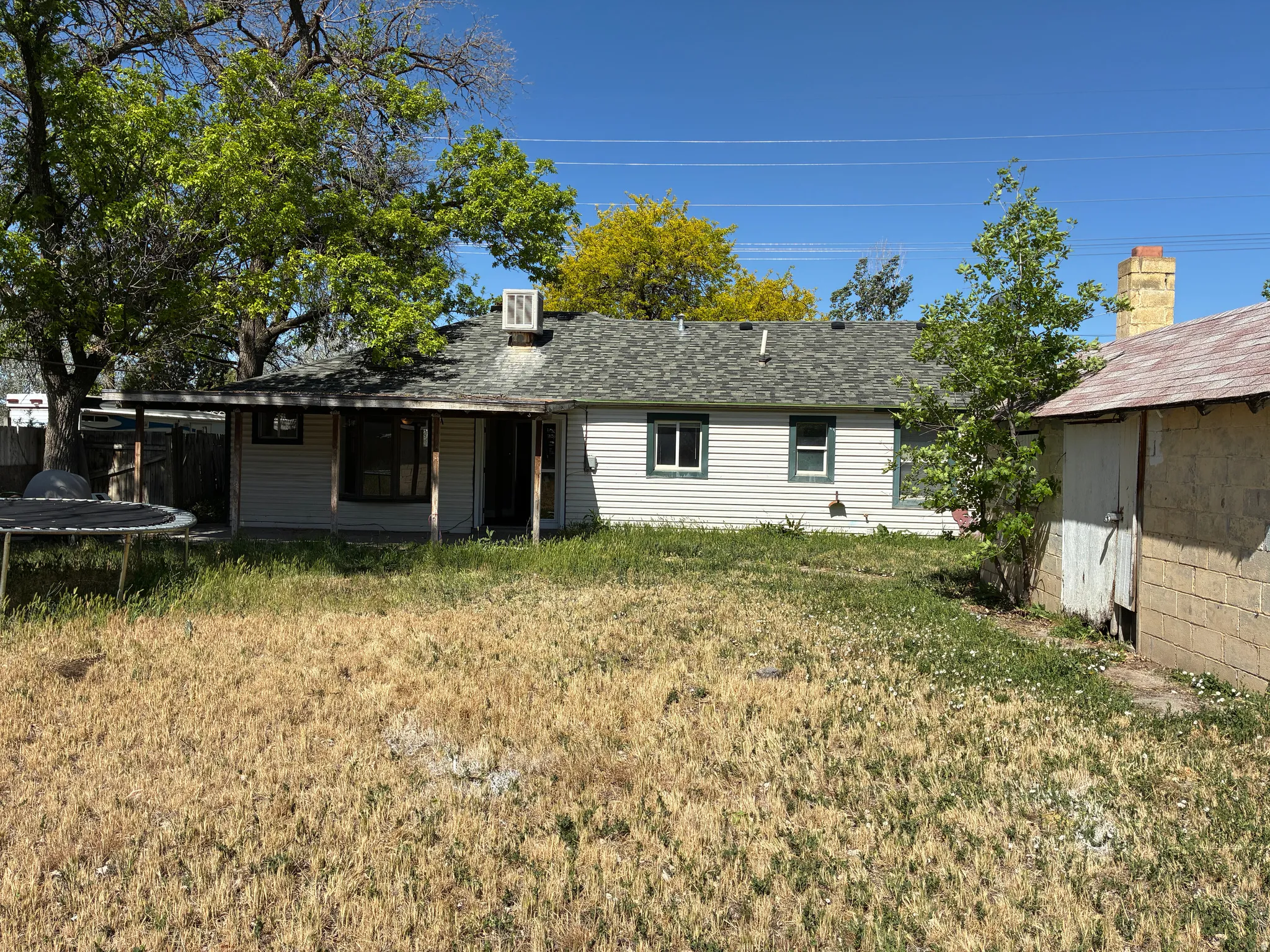 Rear exterior featuring light-colored siding and a covered patio supported by wooden posts