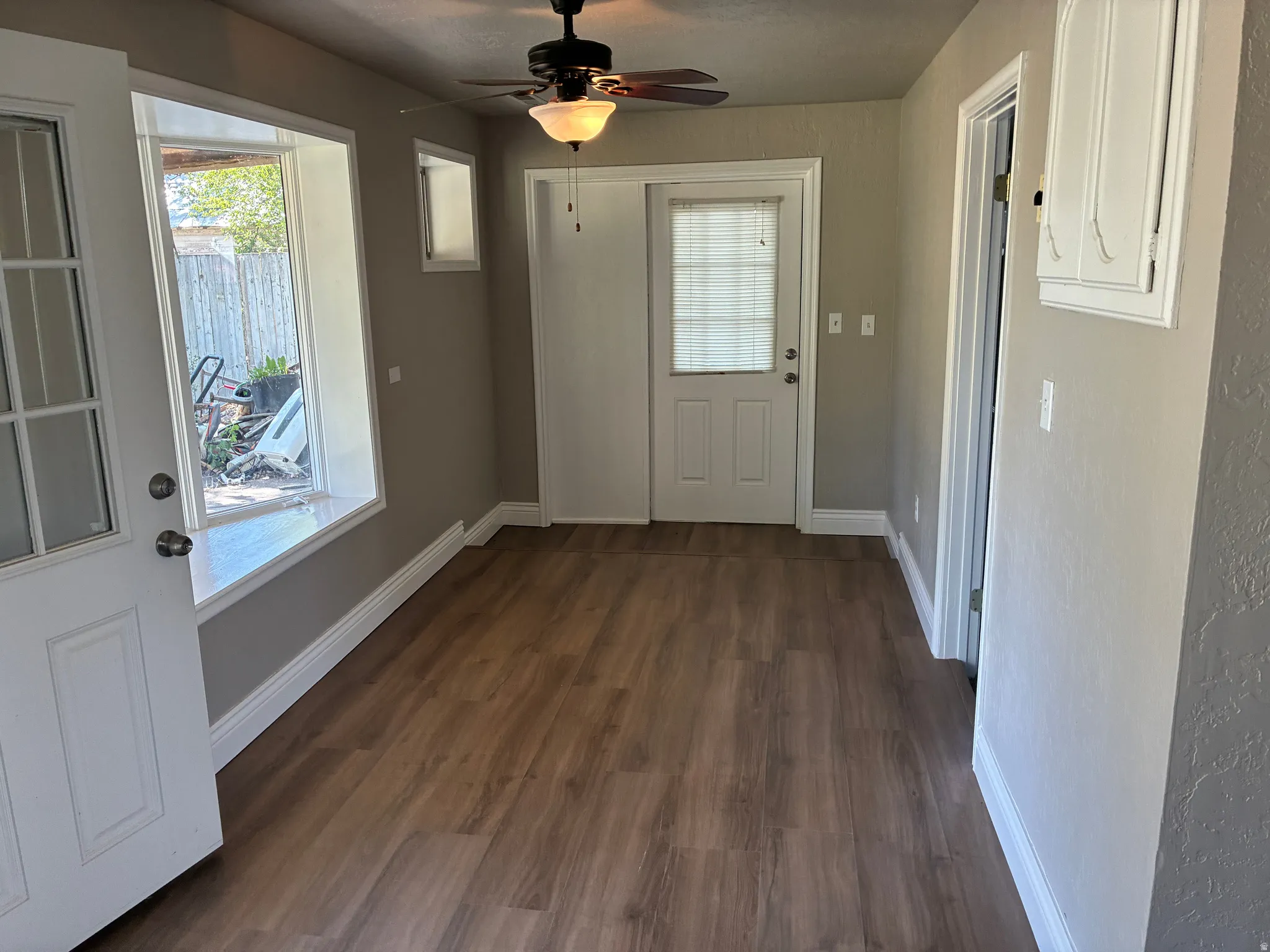 Interior space featuring wood-finish flooring, a contemporary ceiling fan, and painted baseboards