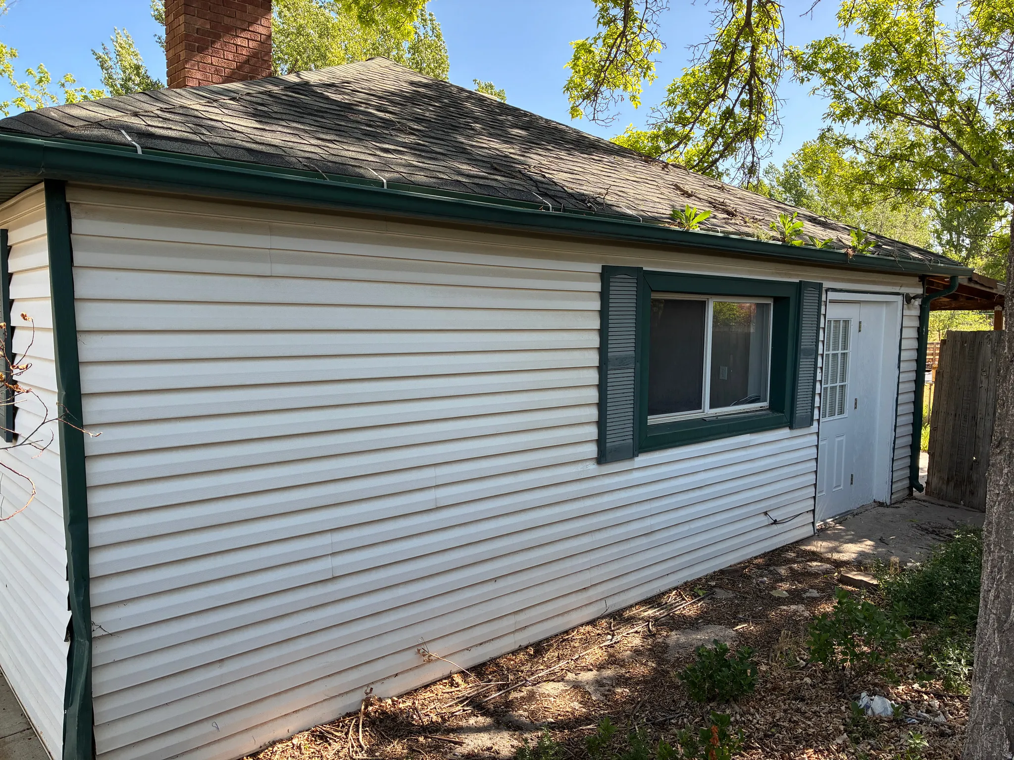 Exterior featuring white horizontal siding, a dark green trim, and a white paneled door with glass inserts