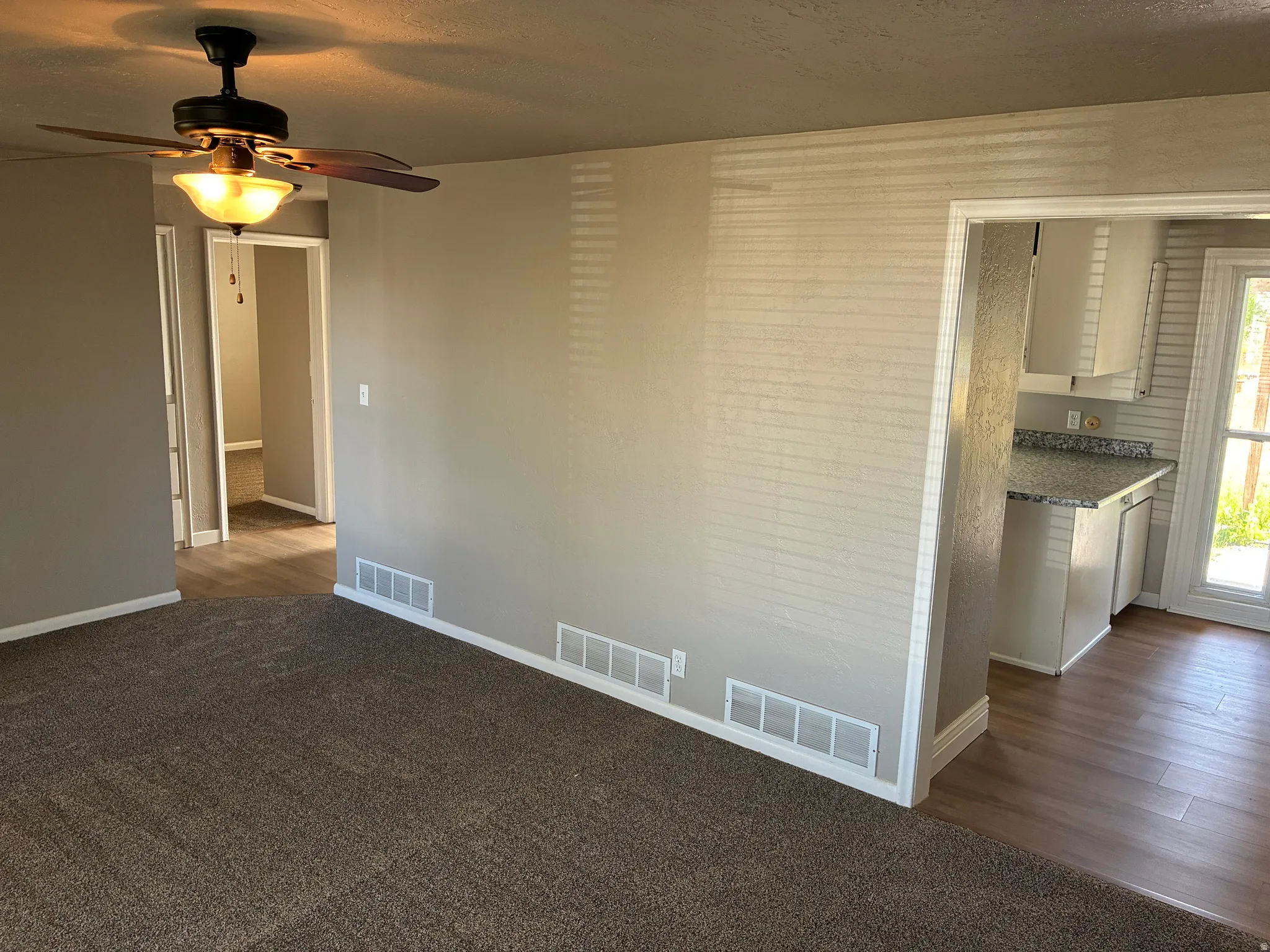 Living area featuring dark brown carpet, a ceiling fan with integrated lighting, and neutral wall paint