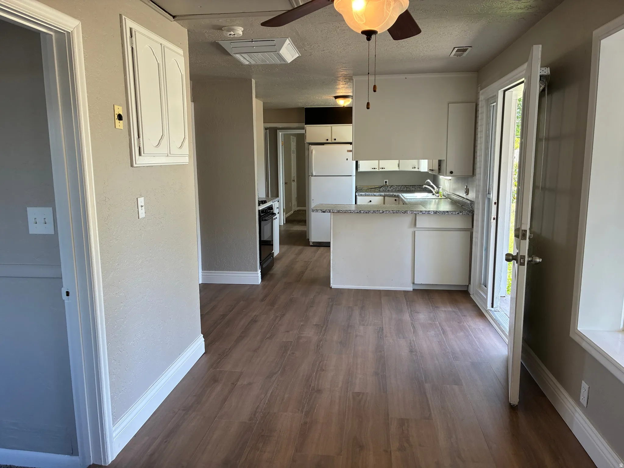 Kitchen with white cabinetry, light-toned countertops, and wood-finish flooring