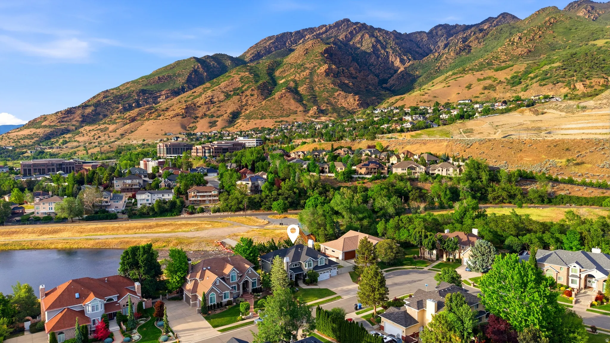 Aerial perspective showcasing a residential neighborhood with mountain backdrop and a body of water