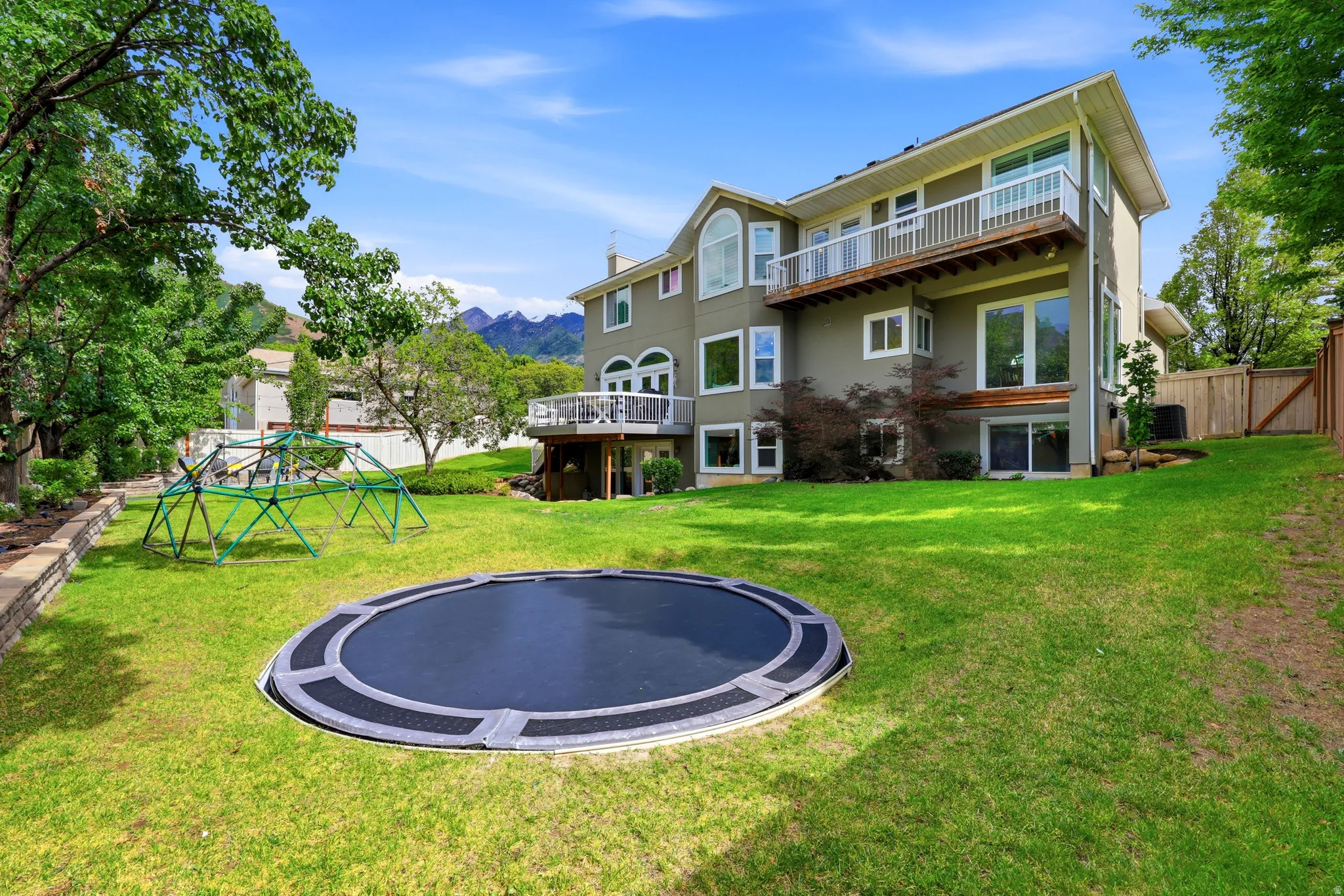 Expansive green lawn with an in-ground trampoline and a retaining wall