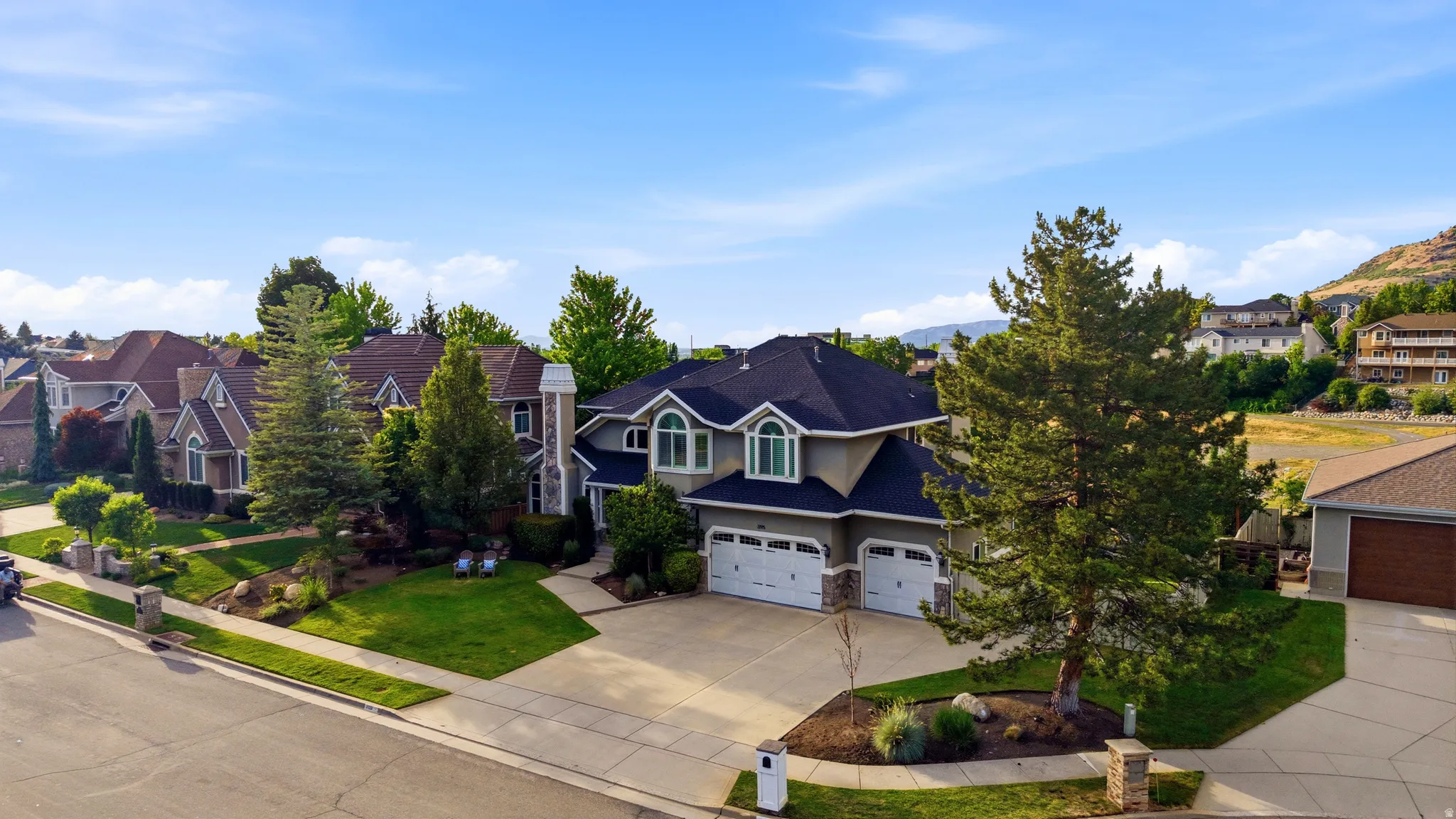 Contemporary residence featuring a three-car garage, stone and stucco exterior, and a prominent arched window dormer