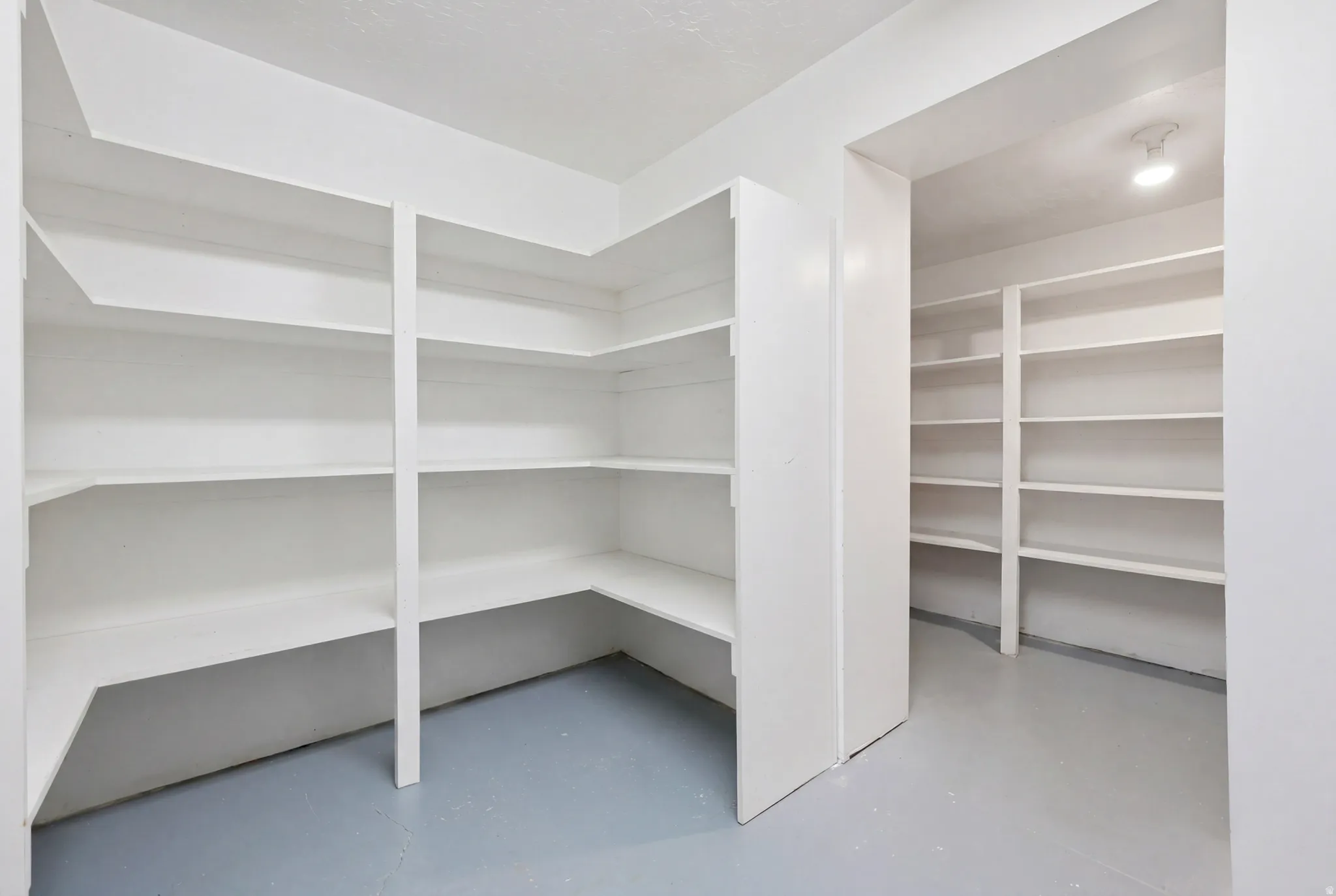 Expansive pantry with multi-level shelving, white painted finishes, and recessed ceiling lighting