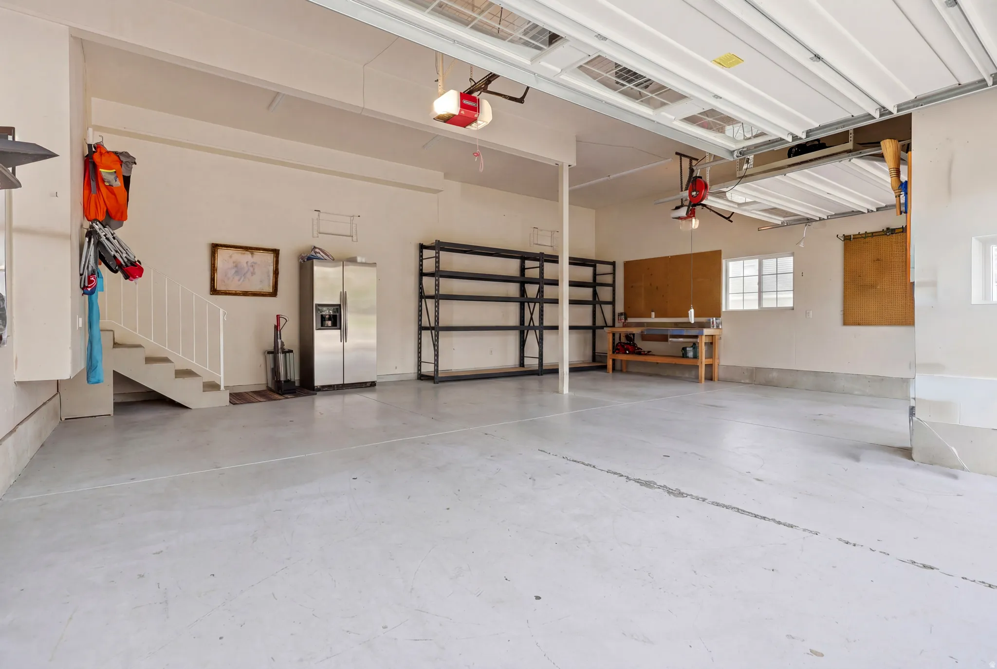 Spacious multi-car garage featuring a painted concrete floor, built-in shelving, and a workbench area