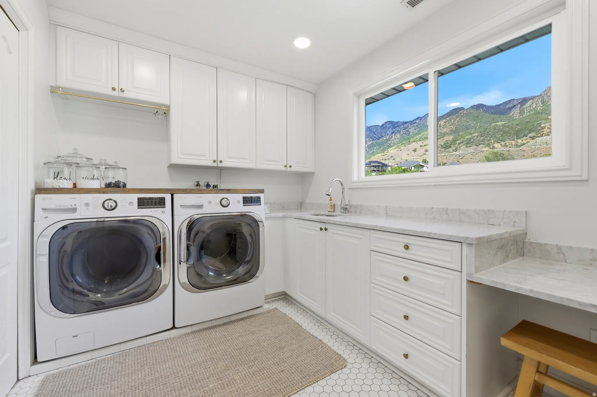 Bright laundry room featuring white cabinetry, a wood-finish countertop, and a built-in sink with a gooseneck faucet