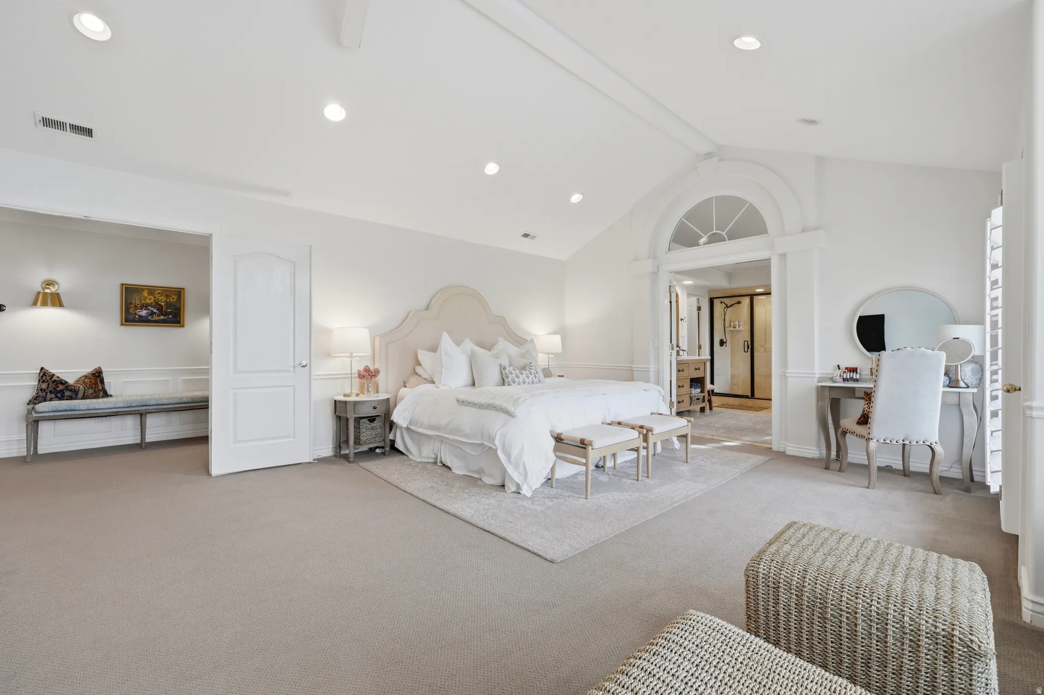 Spacious room featuring vaulted ceilings, recessed lighting, arched doorway, wainscoting, and carpet flooring