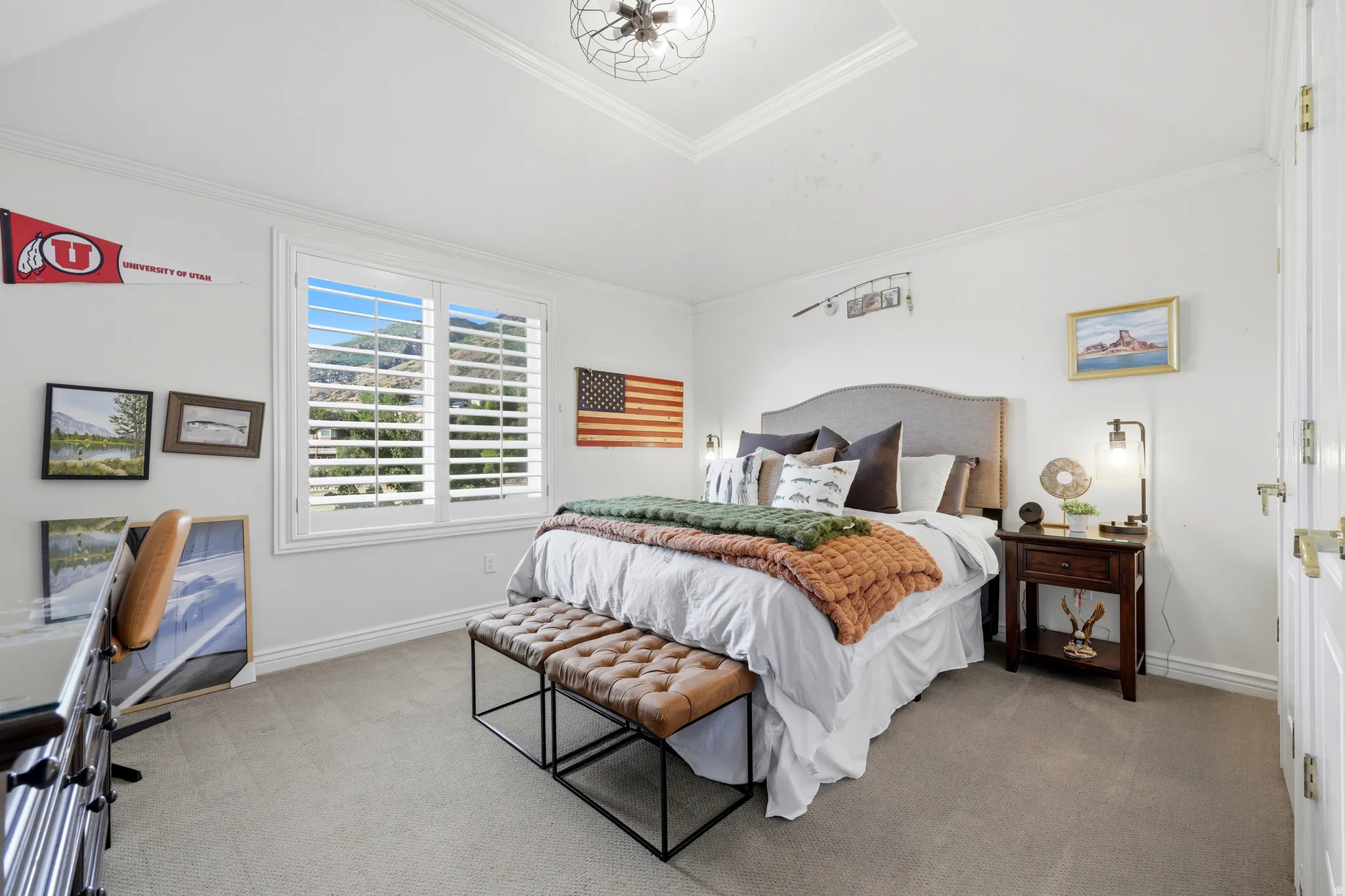 Recessed ceiling with decorative light fixture, large window with white plantation shutters, white paneled door, and carpeted flooring
