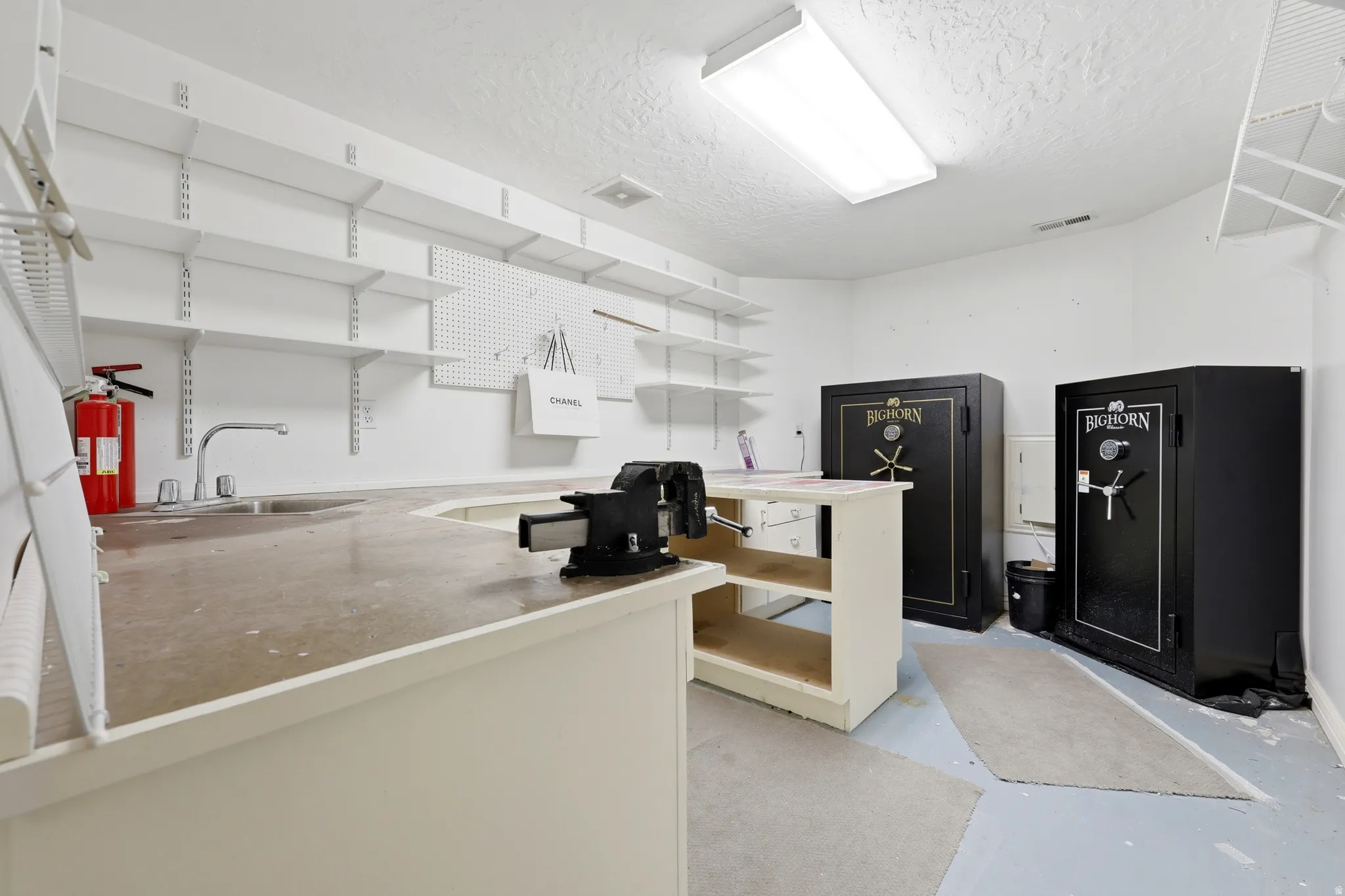 Utility room featuring a built-in workbench with an integrated sink, wall-mounted adjustable shelving, and pegboard storage