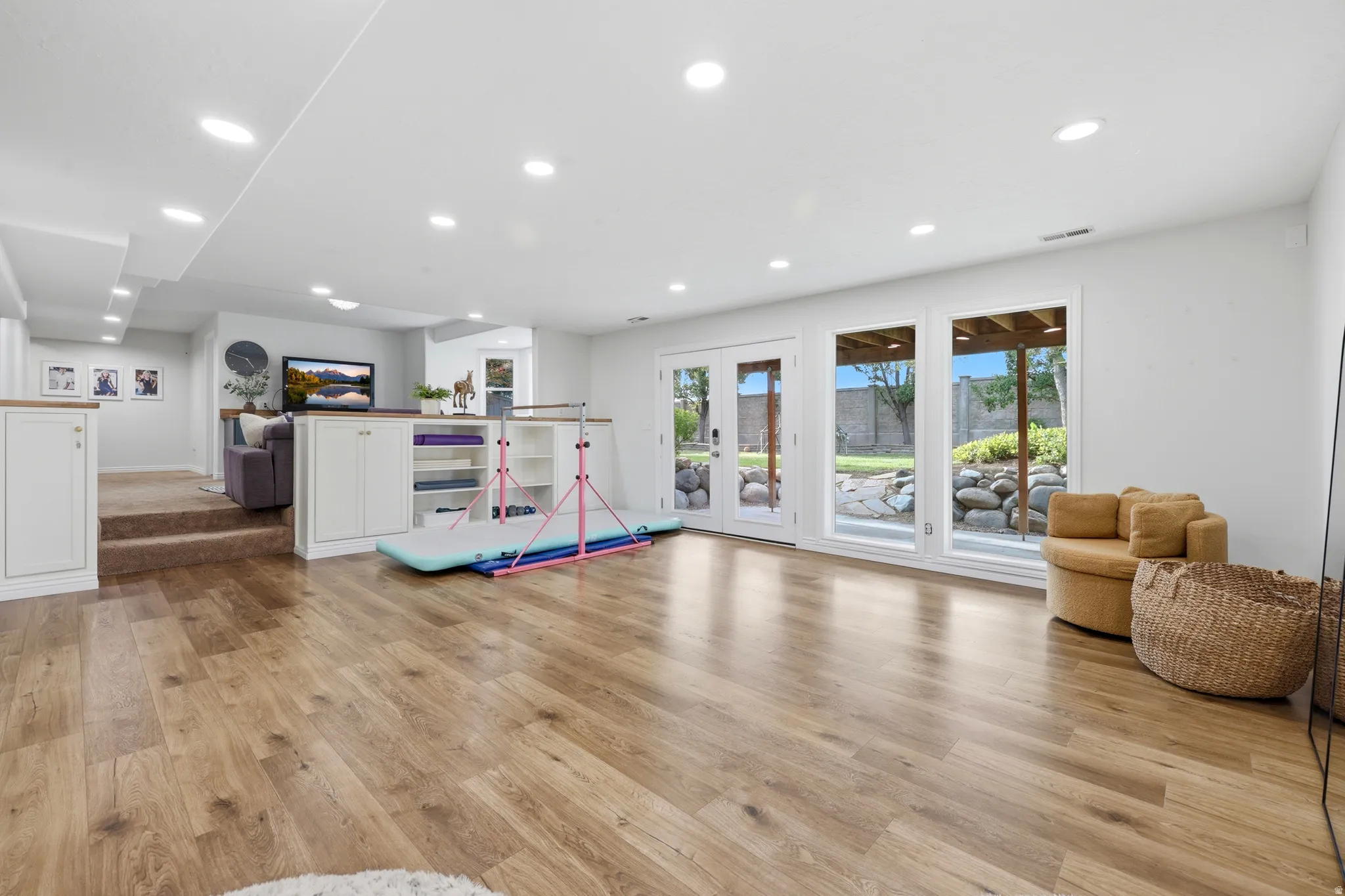 Spacious lower-level area featuring wood-finish flooring, recessed lighting, and white walls