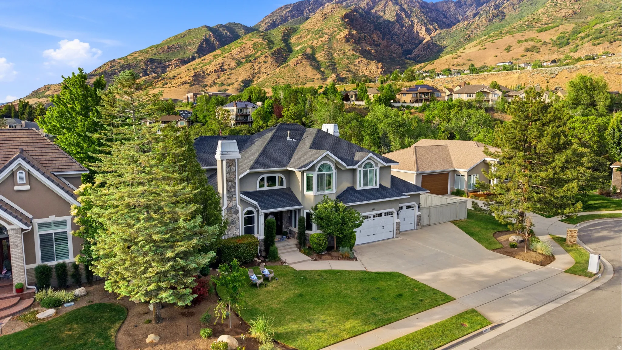 Two-story residence featuring a gray exterior with white trim, arched windows, and a prominent stone chimney