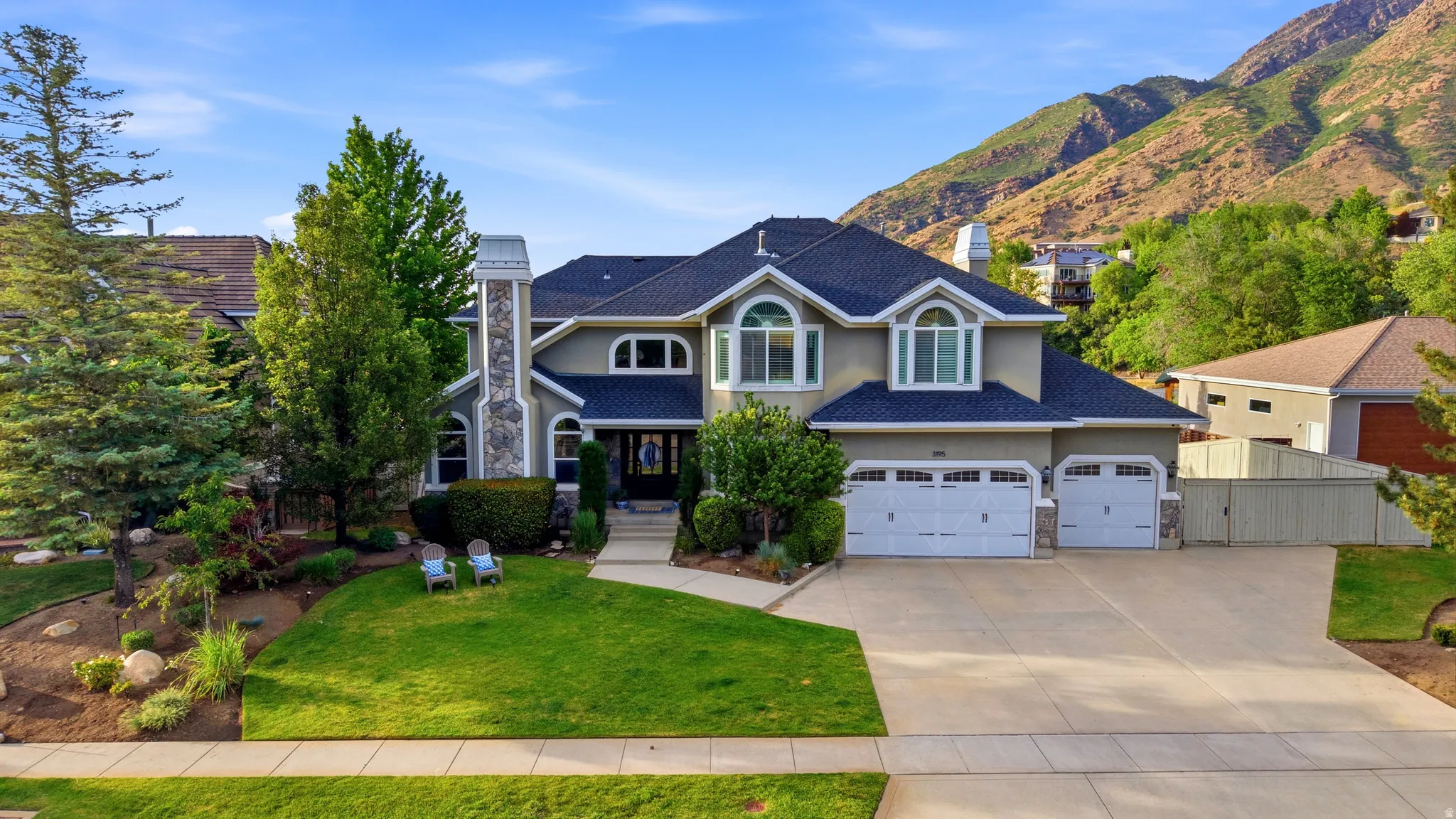 Stately residence featuring a stucco exterior with stone accents, a multi-gabled roofline, and a three-car garage