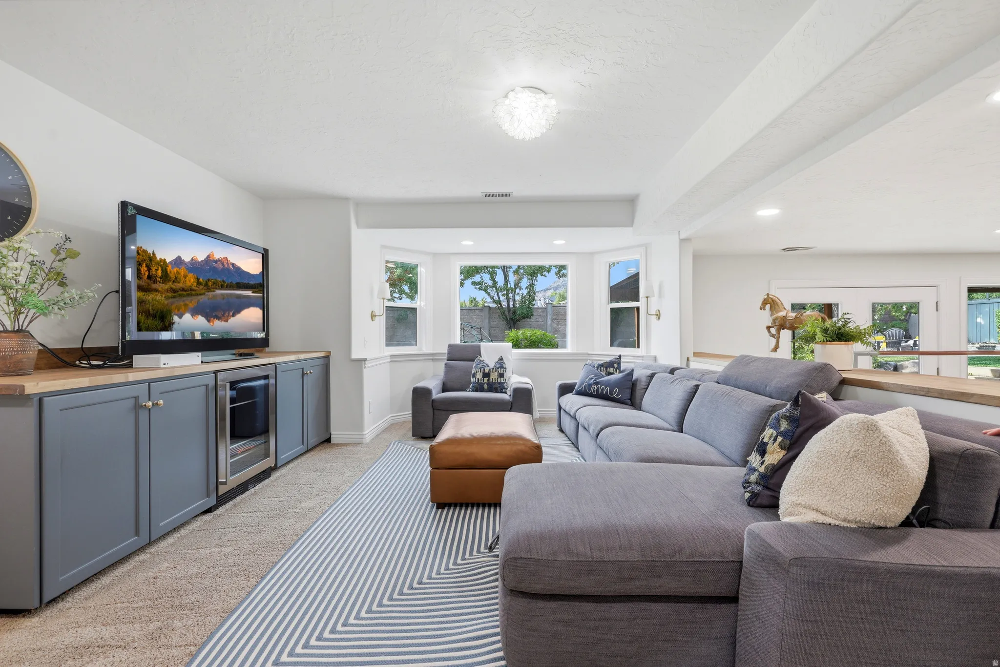 Living area featuring a bay window, recessed lighting, and built-in cabinetry with a beverage cooler and wood-finish countertop