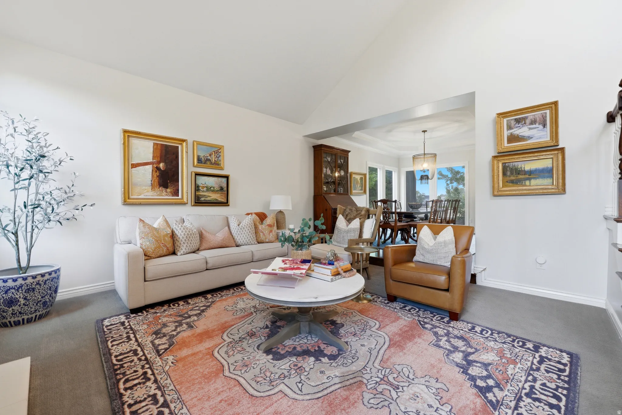 Vaulted ceiling living area with a broad entryway to a dining space, featuring recessed lighting and light-colored wall finishes