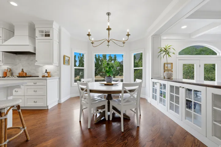 Open-concept living space with dark wood-finish flooring, white cabinetry, and a bay window