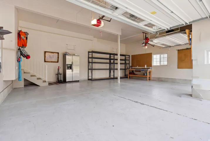 Spacious multi-car garage featuring a painted concrete floor, built-in shelving, and a workbench area