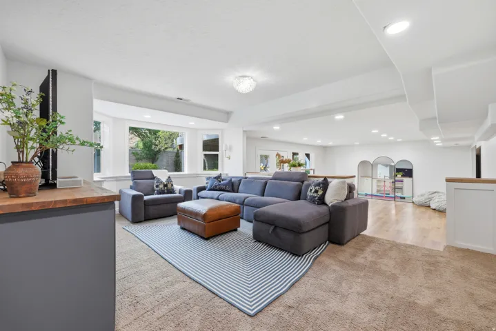 Expansive lower-level living space featuring recessed lighting, a bay window, wood-finish flooring, and a built-in wood-top counter