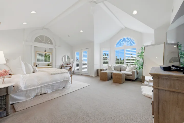 Spacious bedroom with vaulted ceilings, recessed lighting, and light-colored carpeting
