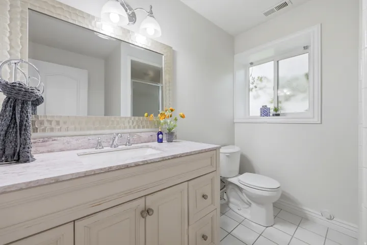 Bathroom vanity with a light-toned countertop, under-mount sink, and chrome faucet