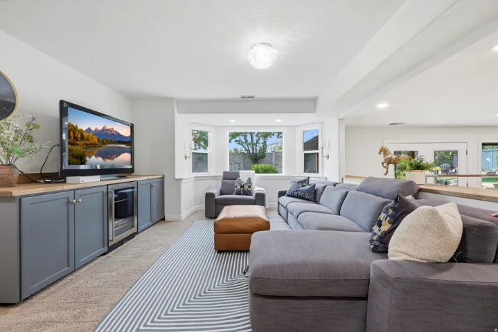 Living area featuring a bay window, recessed lighting, and built-in cabinetry with a beverage cooler and wood-finish countertop