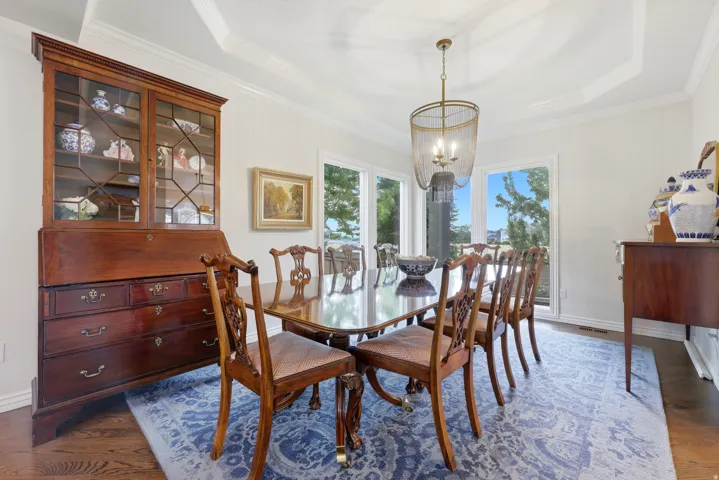 Dining area featuring rich wood-finish flooring, a coffered ceiling, and a contemporary chandelier