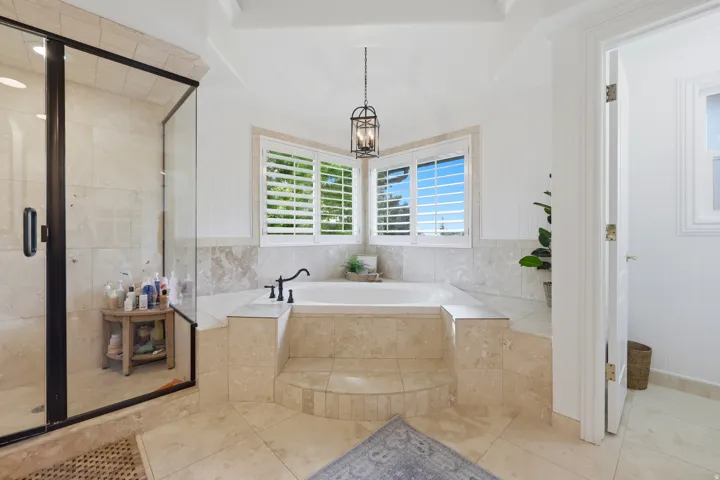 Corner soaking tub with a stepped, tiled surround and matte black fixtures