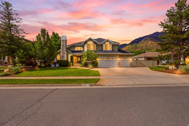 Stucco exterior residence featuring a stone chimney accent, arched entryways, and multiple bay windows