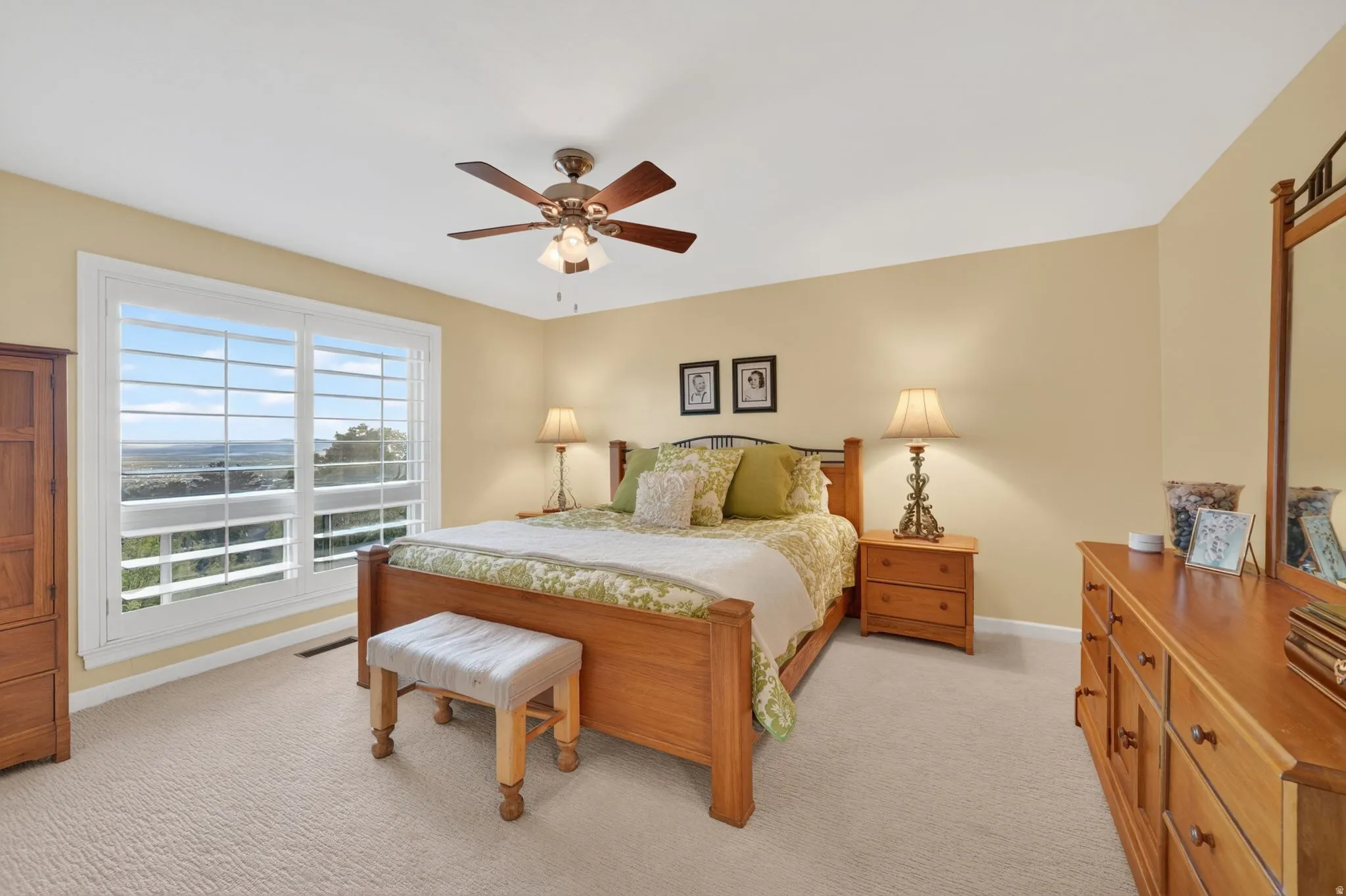 Bright interior space featuring a large window with white louvered shutters, offering expansive outdoor scenery