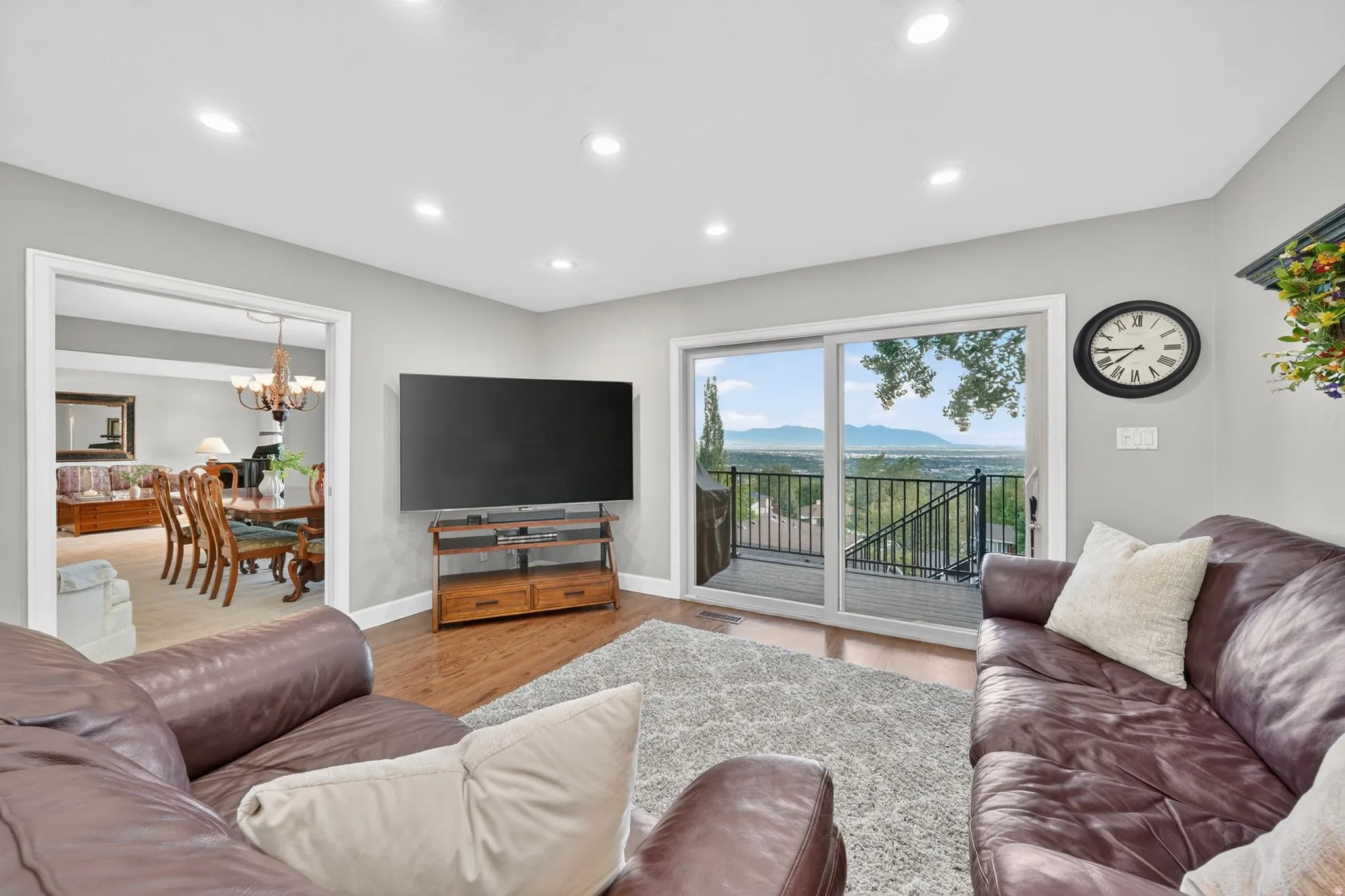Sliding glass doors opening to a deck with metal railings and mountain scenery