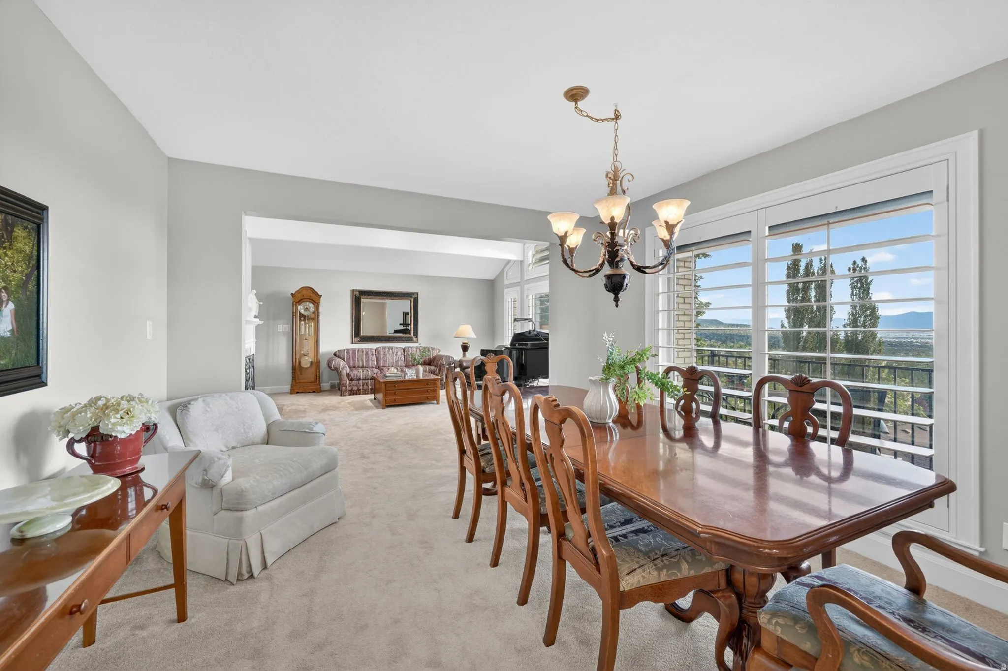 Formal dining space featuring a chandelier, large windows with shutters, and expansive outdoor scenery