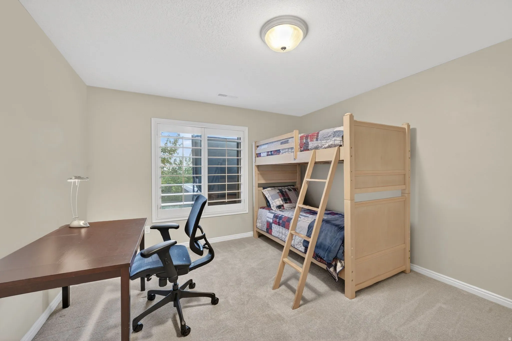 Neutral-toned room featuring a large window with white plantation shutters, a semi-flush mount ceiling light, and light-colored carpeting