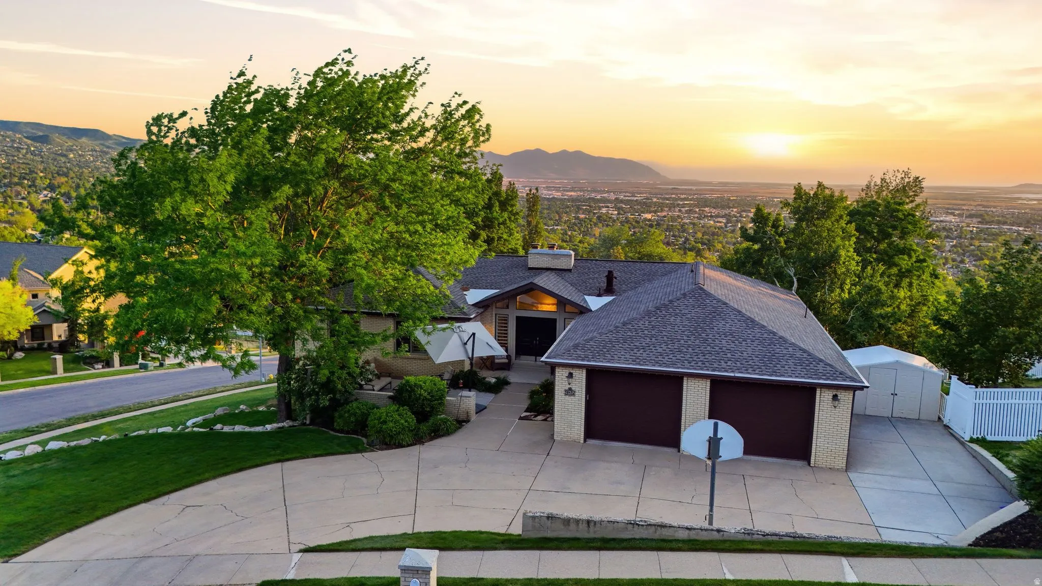 Single-family residence featuring a two-car garage with dark brown doors, a paved driveway, and mature landscaping