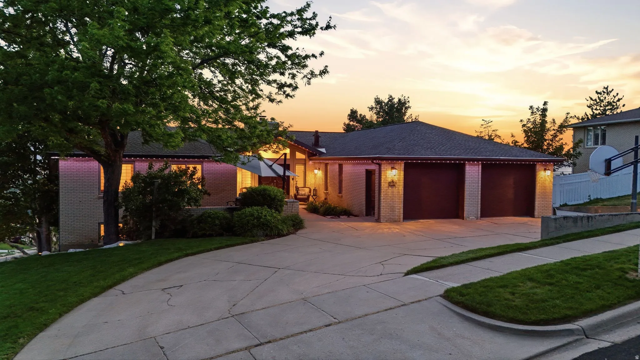 Split-level property featuring a multi-car driveway, attached two-car garage, and established landscaping