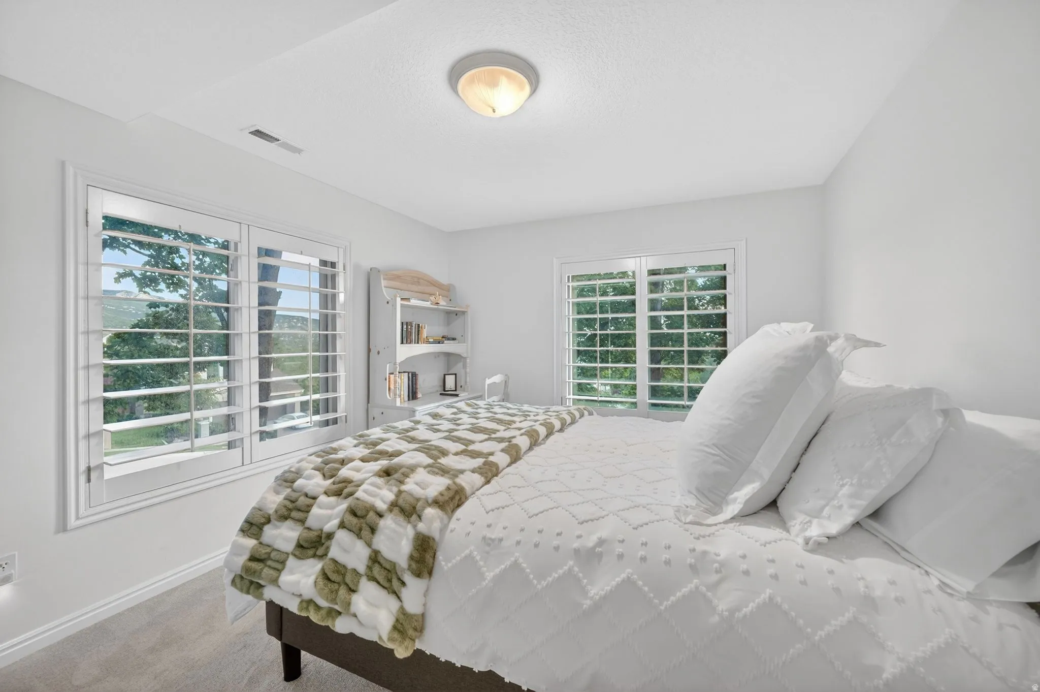 Bright room featuring two windows with white plantation shutters