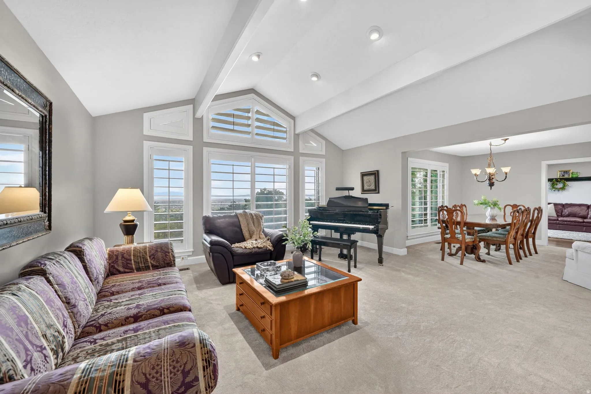 Vaulted ceilings with exposed beams complement the expansive window wall featuring plantation shutters
