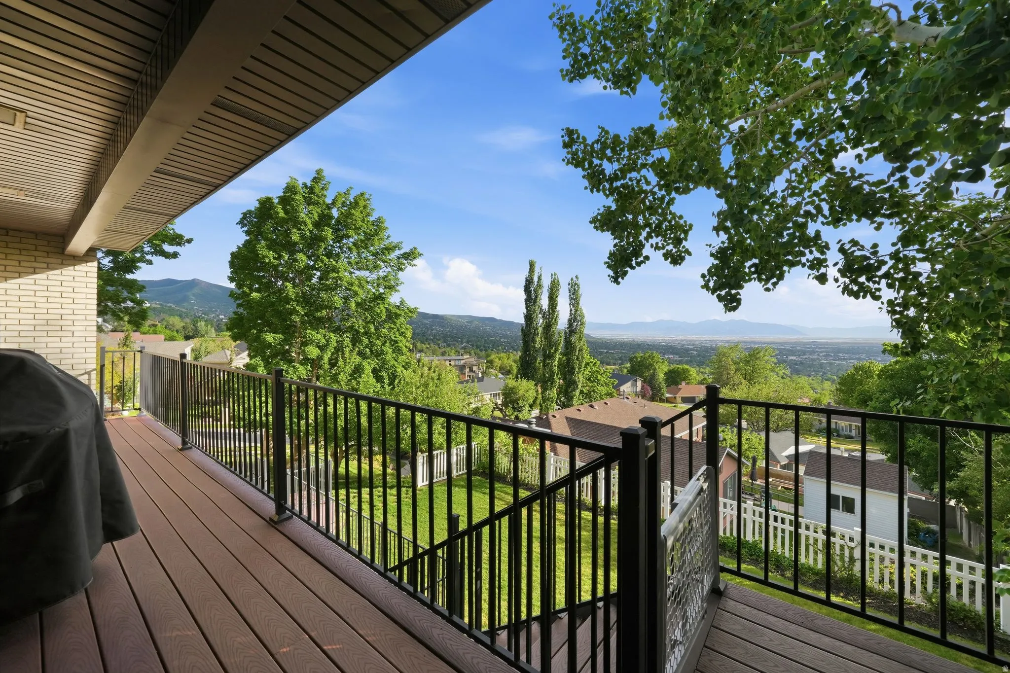 Expansive outdoor deck featuring composite decking, black metal railings, and a partial covered ceiling