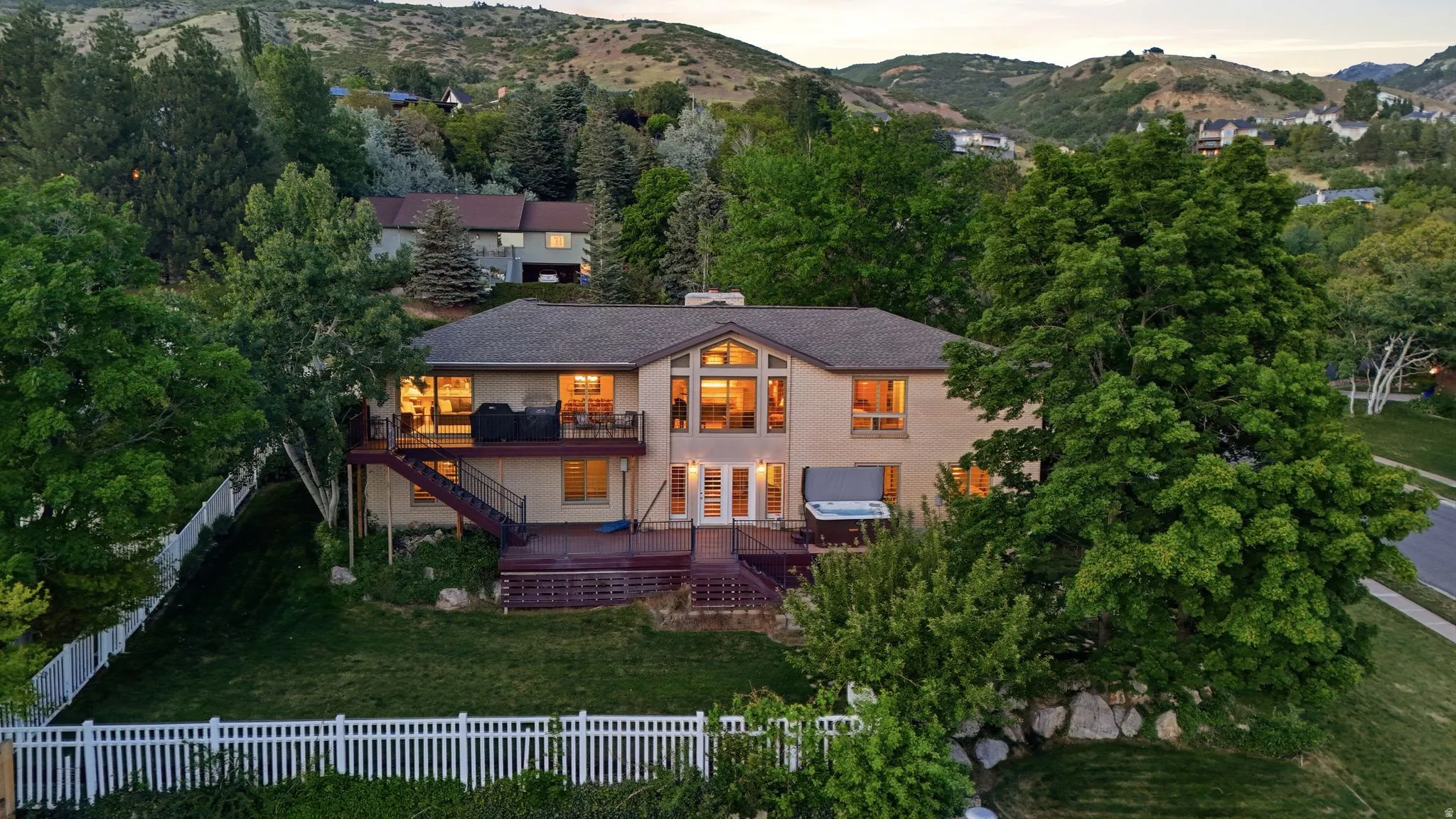 Rear exterior of a multi-story residence featuring a large deck with an integrated hot tub