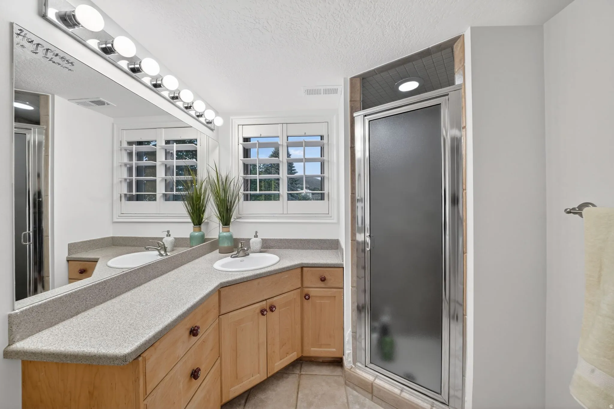 Bathroom featuring an extended vanity with dual undermount sinks and light-toned countertops