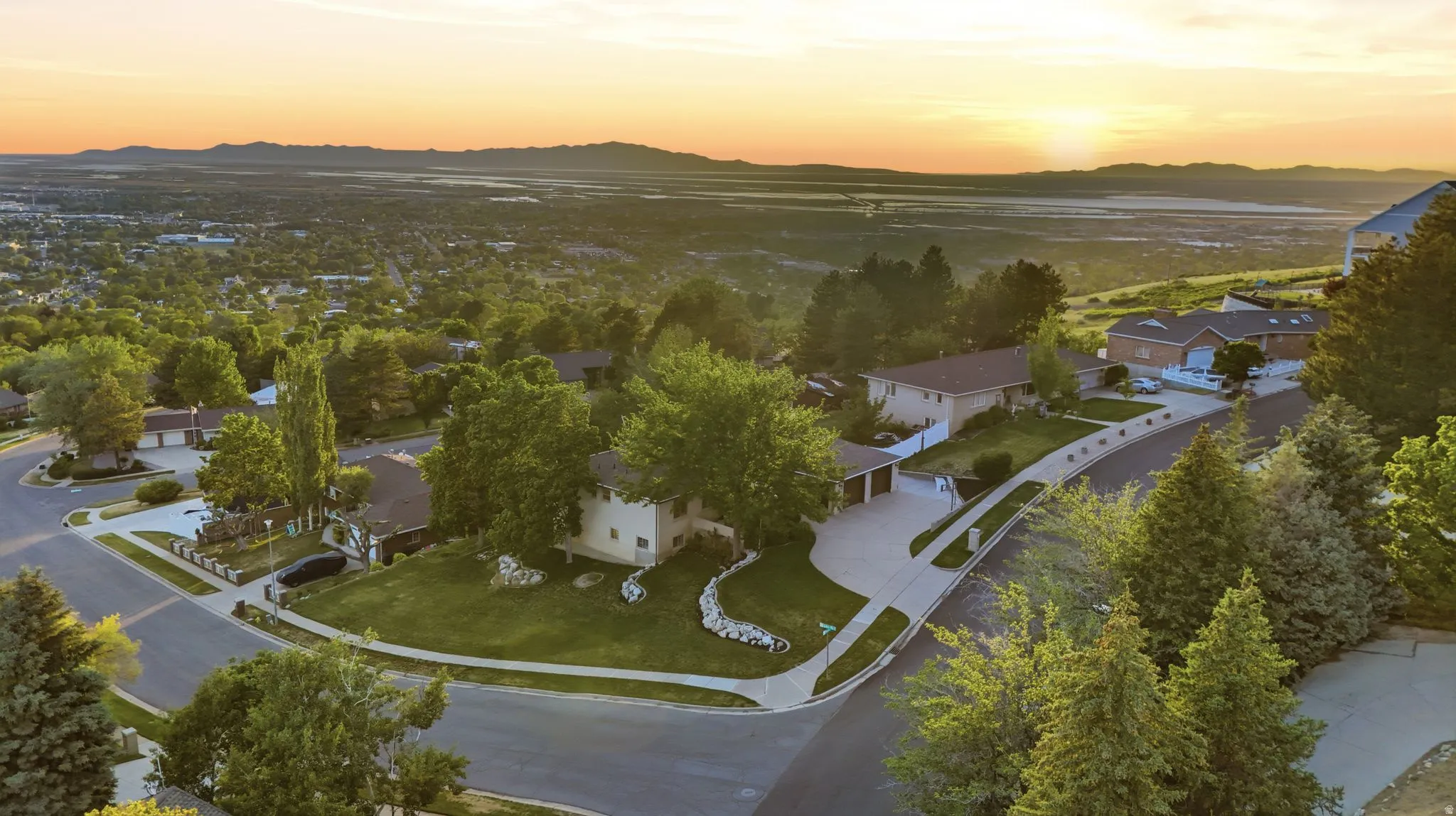 Elevated residential setting featuring mature trees, landscaped lots, and paved roadways