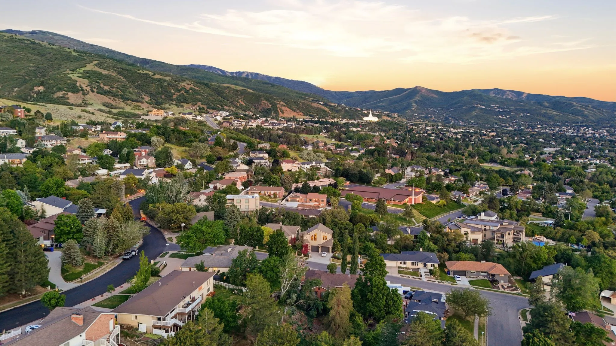 Expansive residential area featuring a mountainous backdrop, abundant mature trees, and diverse architectural styles