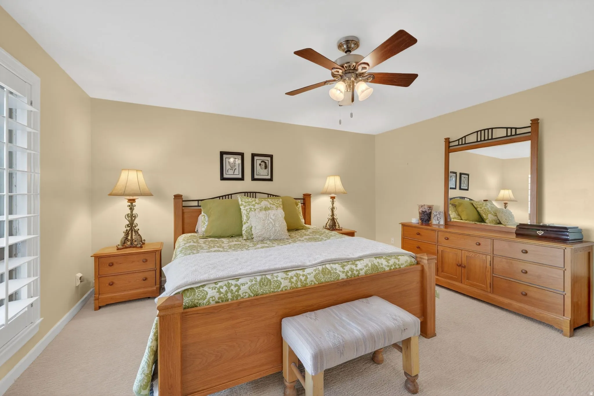 Spacious bedroom featuring light neutral wall paint, soft carpet flooring, and a ceiling fan with integrated lighting