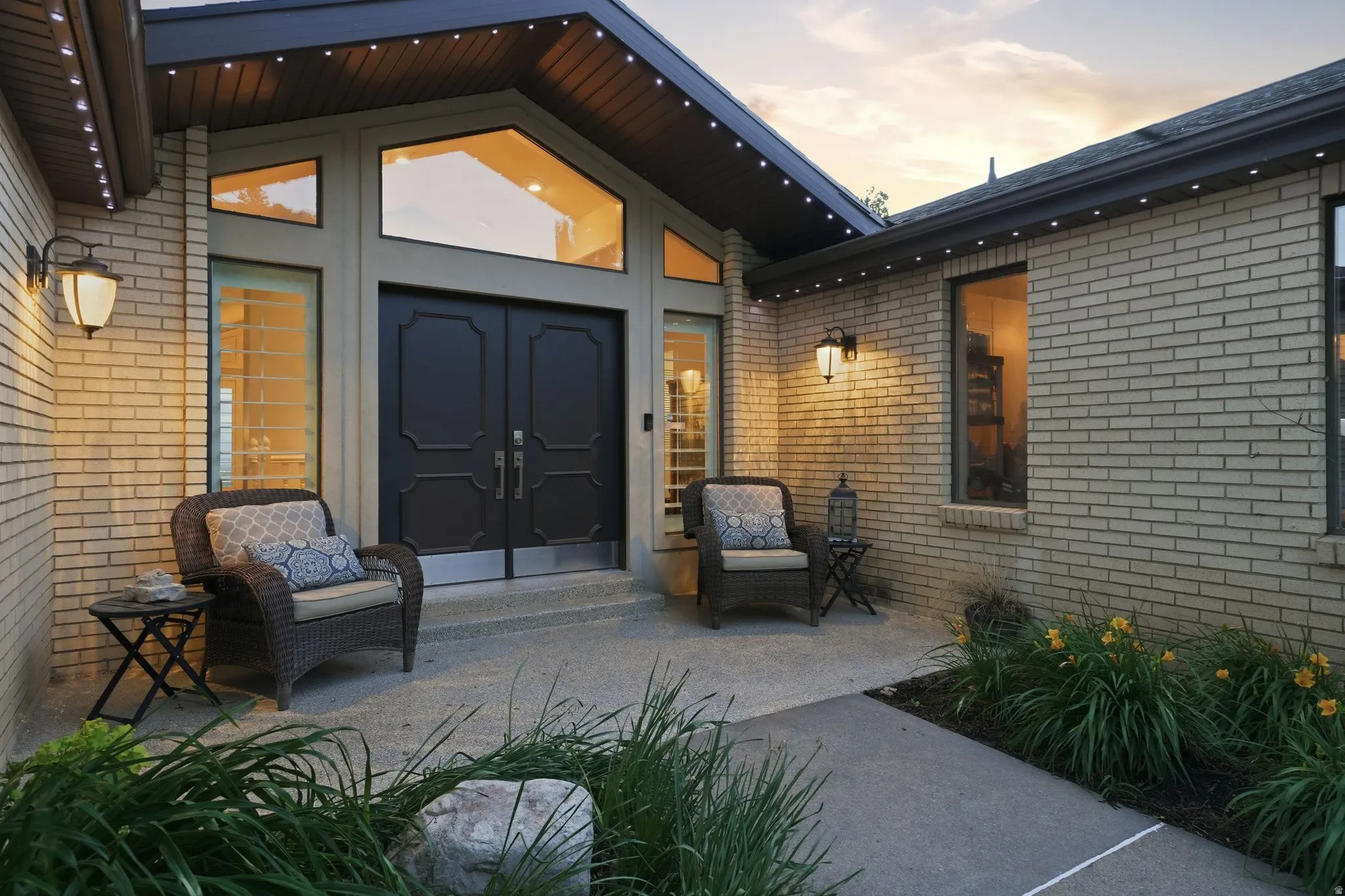 Brick exterior featuring a gabled entryway with dual black panel doors and flanking sidelights