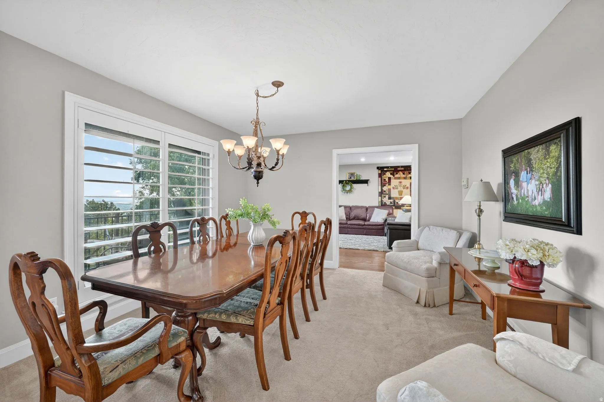 Carpeted room with light grey walls and a large window featuring white plantation shutters