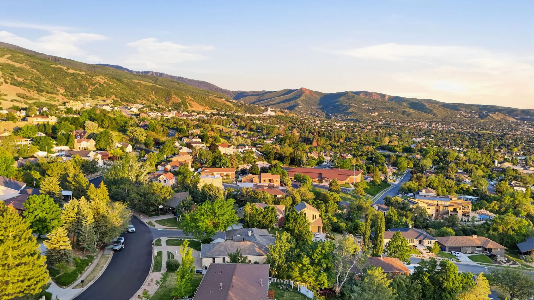 Residential neighborhood featuring mature trees and mountain backdrops